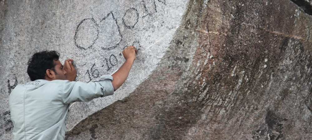 Man writing on a heritage rock