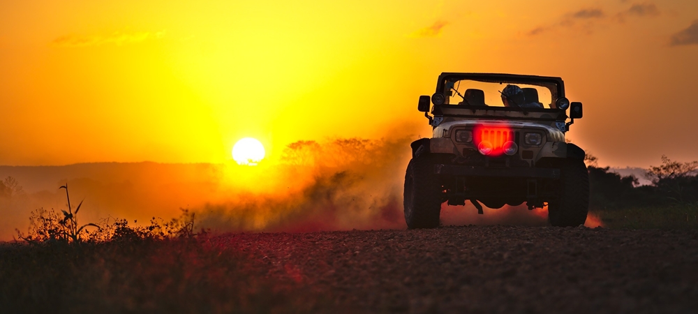 A jeep parked in the backdrop of a sunset