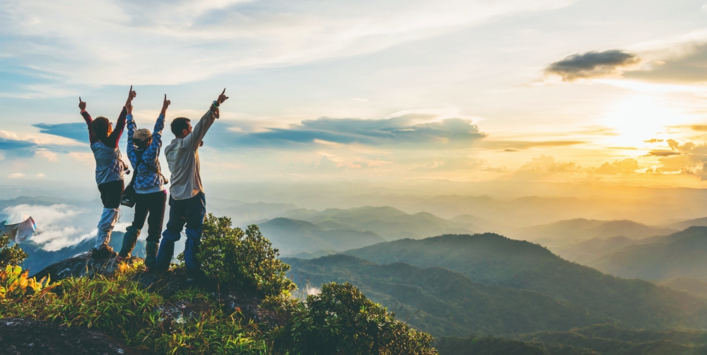 Three tourists reach the top of a mountain and scream