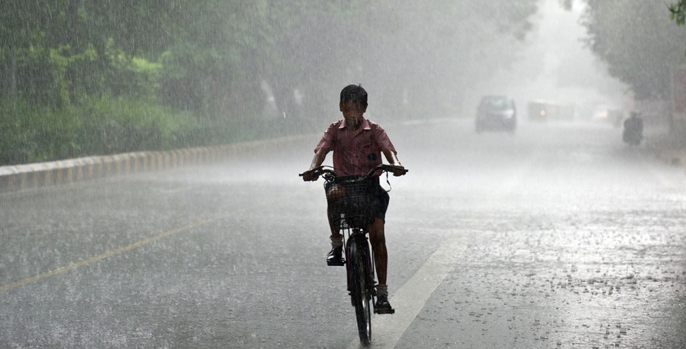 A boy riding his bicycle in the rain