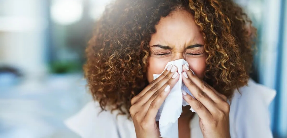 Woman sneezing into a kerchief