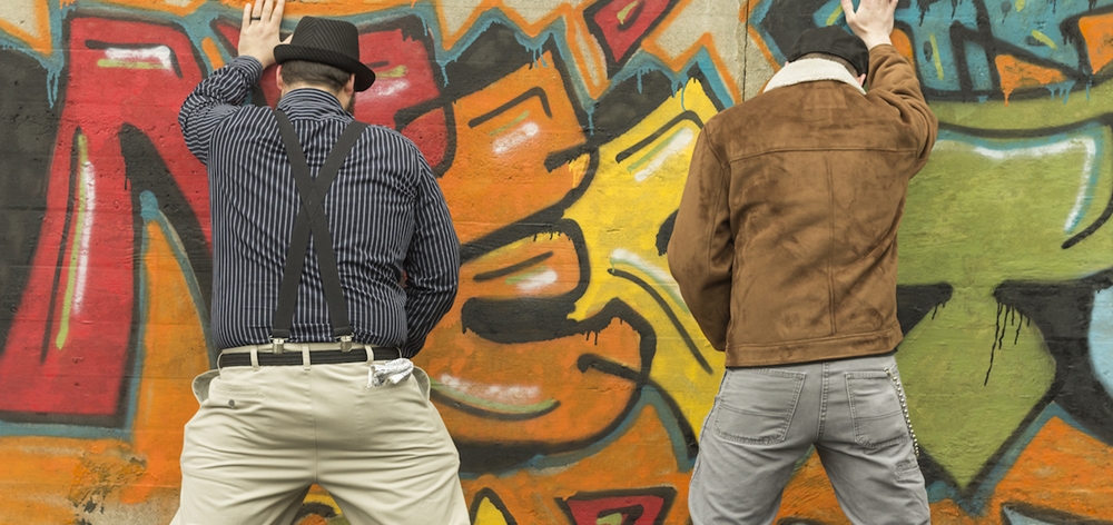 Two men peeing on a wall in public